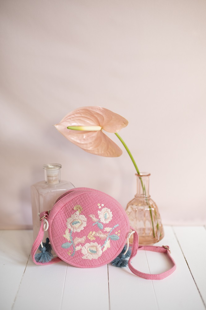 girls-bag-suzy-strawberry-1 Runde Handtasche, rosa Stoff, florale Stickerei, Blumenmuster, Quastenanhänger, Schulterriemen.