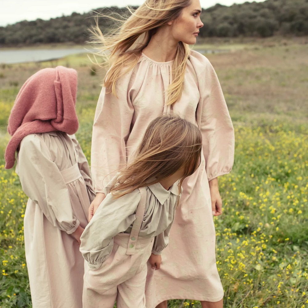 Damask-Woman-Dress Frau mit langem, beigen Kleid; Mädchen mit rosa Kapuzenpullover und beigem Kleid; Kind mit beiger Bluse und rosa Hose mit Hosenträgern; natürliche Umgebung.