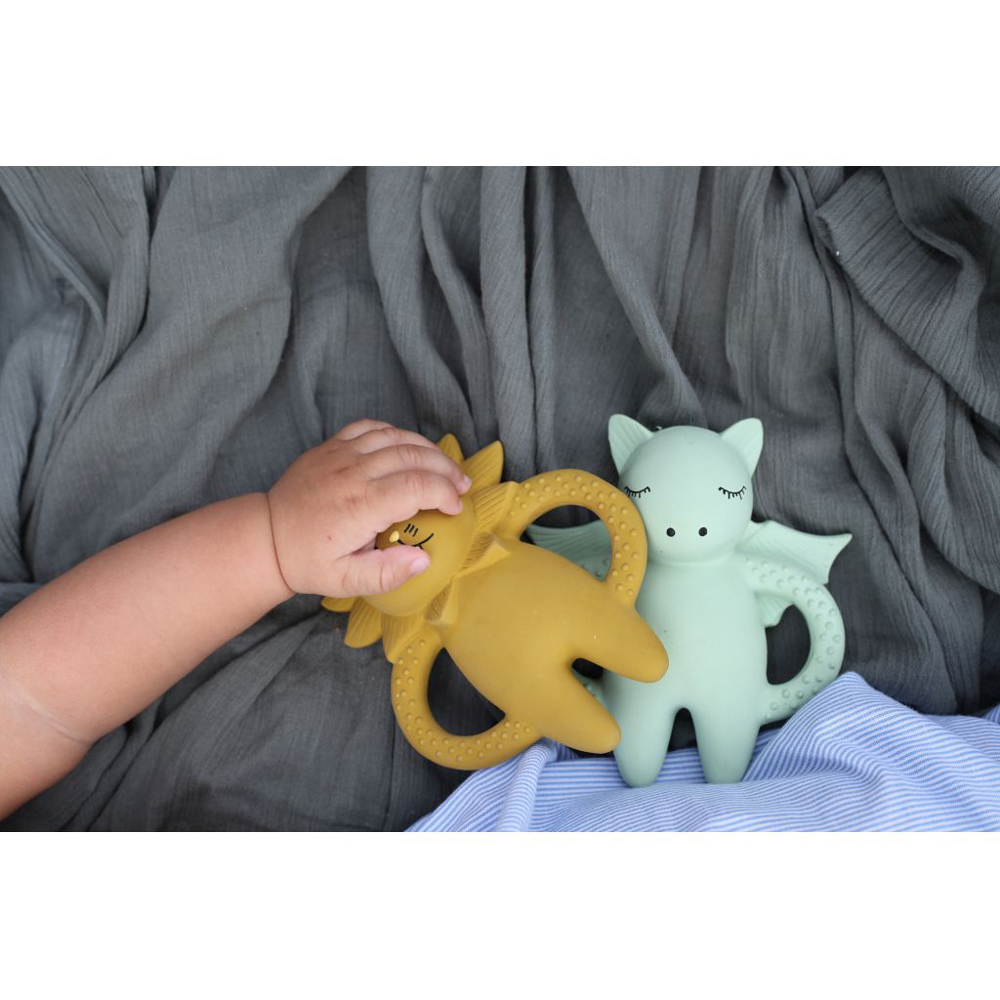 KS1222-Extra-2 Kautschuk-Beißringe, Drache-Design, senfgelb und mintgrün, strukturierte Oberflächen, schlafende Augen, grauer Hintergrund, Babyhand berührt gelbes Spielzeug.