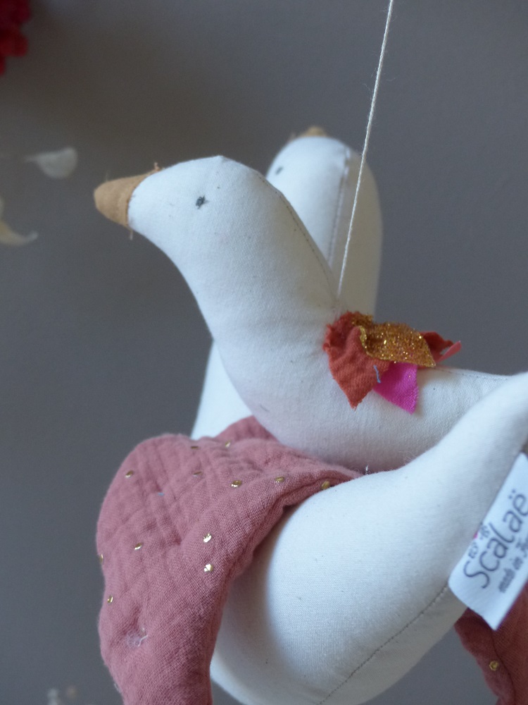 P1210966 Stoffvogel, weiß, hängend, goldener Schnabel, roter Schal, goldene und pinke Flügeldeko, rosa Stoffdecke mit goldenen Punkten.