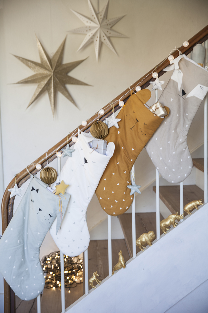 IMG_0824 Weihnachtssocken, vier Stück; Farben: Blau, Weiß, Braun, Grau; Tier- und Sternmuster; aufgehängt an Treppengeländer; dekoriert mit kleinen Kugeln und Sternanhängern.