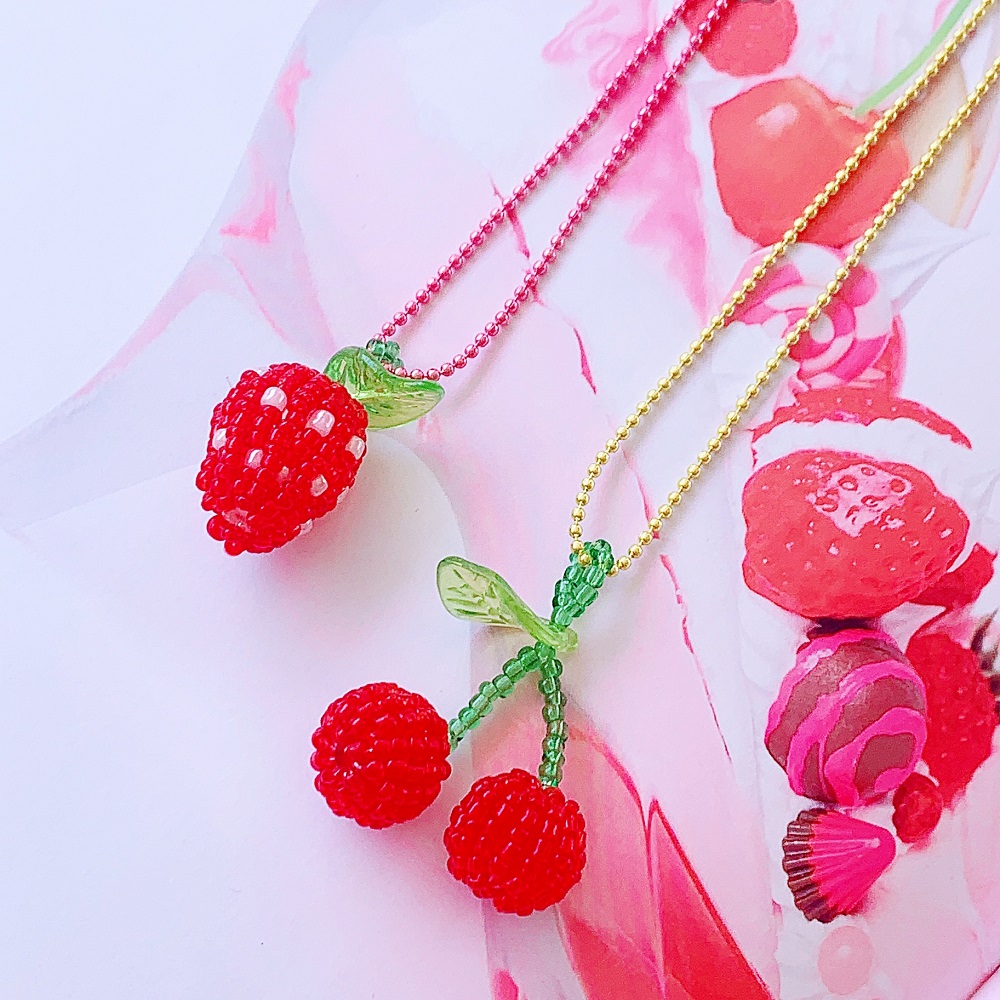 893da0b21735400399b782294f2906b38e6fbad1c18bec826300599b16044fcb Perlenketten, Erdbeermotiv mit rosa Kette, Kirschmotiv mit gelber Kette, rote Perlen, grüne Blätter aus Kunststoff, verspieltes Design.