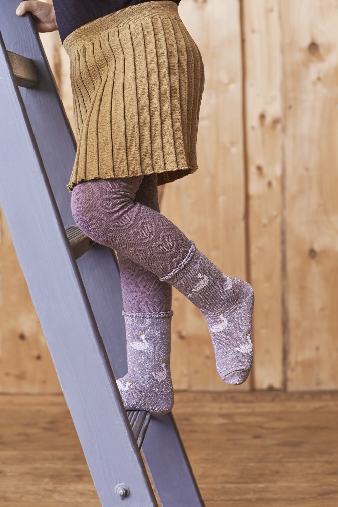 MP-kids_020 Kindersocken, lila, Schwan-Motiv; Kinderstrumpfhose, altrosa, geometrisches Muster; Kinderrock, braun, plissiert; Kind auf Leiter.