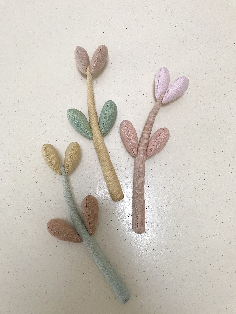 06F45759-C603-4881-8ADC-58EFFD58F9BF-002 Stoffspielzeug Zweige, Pastellfarben, grüne und rosa Blätter, cremefarbene und hellblaue Stiele.