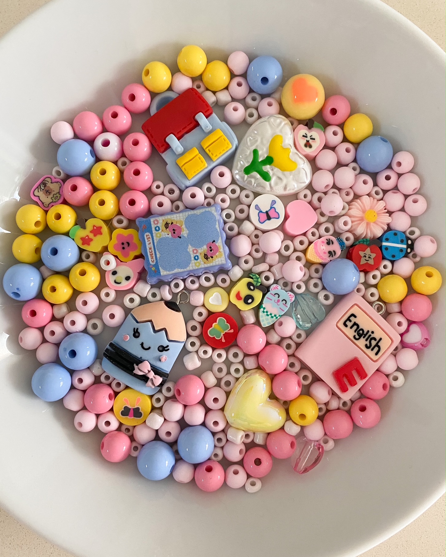 Bunte Perlenmischung, runde Perlen in Rosa, Blau, Gelb; Schmuckanhänger in Form von Herz, Stift, Buch; Dekor mit Blumen- und Tiermotiven.