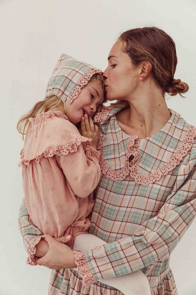 LIAW21_40_W_check_mama-bebe_closeup_1 Mutter und Kind im Partnerlook; Mutter: kariertes Kleid mit Spitze, Pastelltöne; Kind: rosa Kleid mit Stickerei, Spitze, gestreifte Haube; zärtliche Pose, inniger Moment.