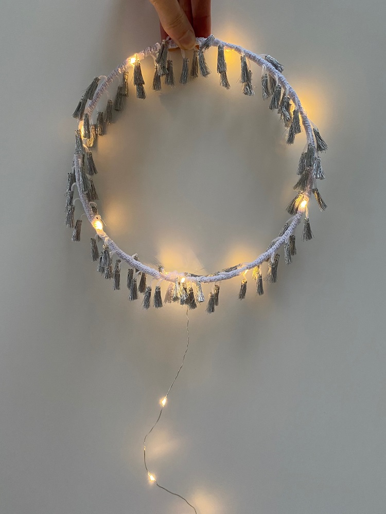 IMG_01321QQiX1INTkrAJ Lichterkranz, rund, beige, graue Quasten, warmweiße Lichter, batteriebetrieben, handgehalten, dekorativ.