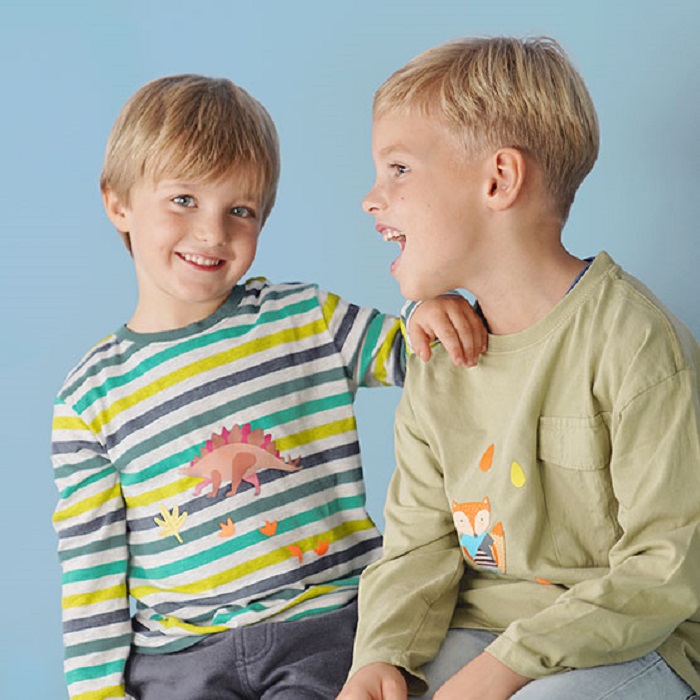 fabfabstickers_Stoffsticker_n Kinderoberteile, gestreiftes Shirt mit Dinosaurier-Aufdruck, mehrfarbig; olivgrünes Shirt mit Fuchs-Motiv; blaue Hosen; Hintergrund blau.