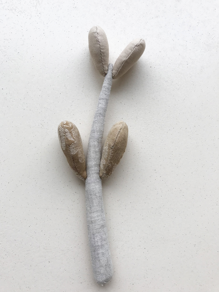 IMG_1339 Stoffspielzeug, grau-beige, pflanzenartig, zwei kurze und zwei längere abgerundete Blätter.