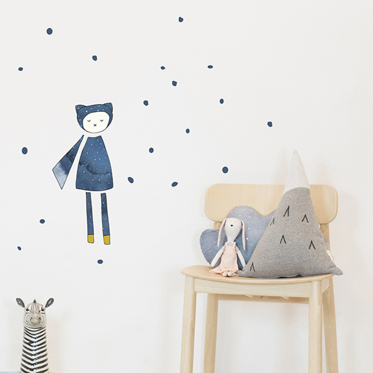wallsticker_kids_fabelab_magician_detail-1 Wandaufkleber: blauer Charakter mit Schal, Punkte; Holzstuhl: Kissen grau-blaue Wolke, grauer Bergkissen mit schwarzen Dreiecken, Stofftier Hase; Zebrafigur im Vordergrund.