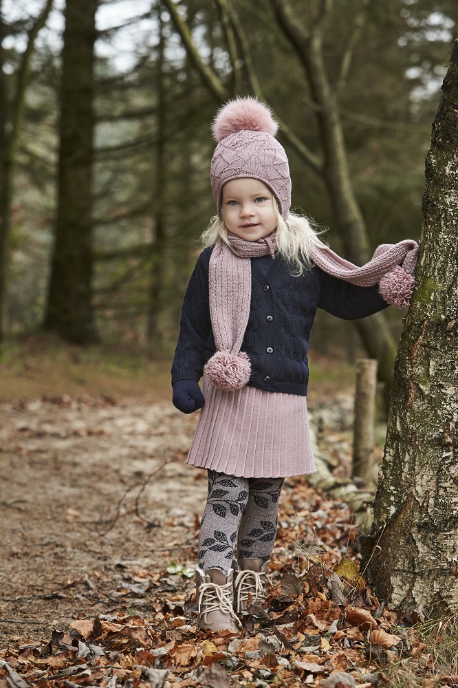 MP-kids_031 Kleinkind Winterkleidung, dunkelblaue Strickjacke, rosa Strickmütze mit Bommel, passender Schal, rosa Rock, gemusterte Leggings, beige Boots.
