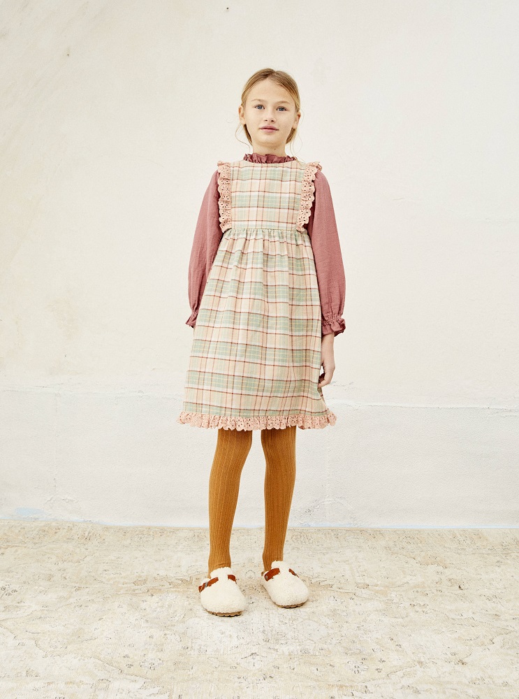 LIAW21_35_check_4 Mädchenkleid, kariert, pastellfarben, rosa Rüschen, lange Ärmel in Altrosa, gestrickte Strumpfhose, senfgelb, Hausschuhe, cremeweiß, rote Details.
