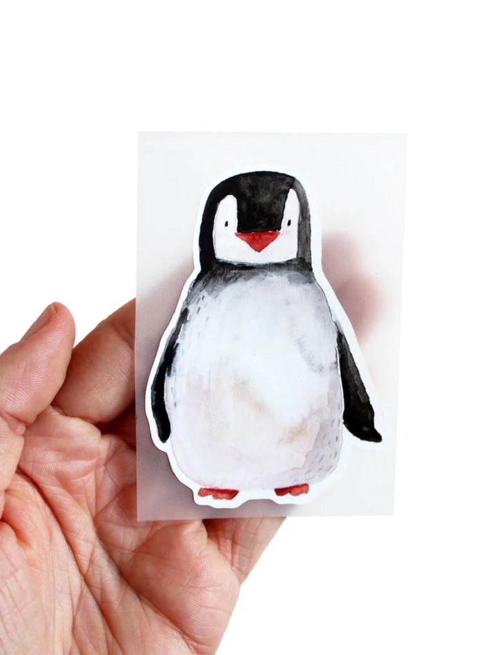 BuegelbildPinguinaufderHand_700x Sticker, Pinguin-Motiv, schwarz-weiß-grau, rote Nase und Füße, rechteckige Form, glatte Oberfläche, handgehalten.