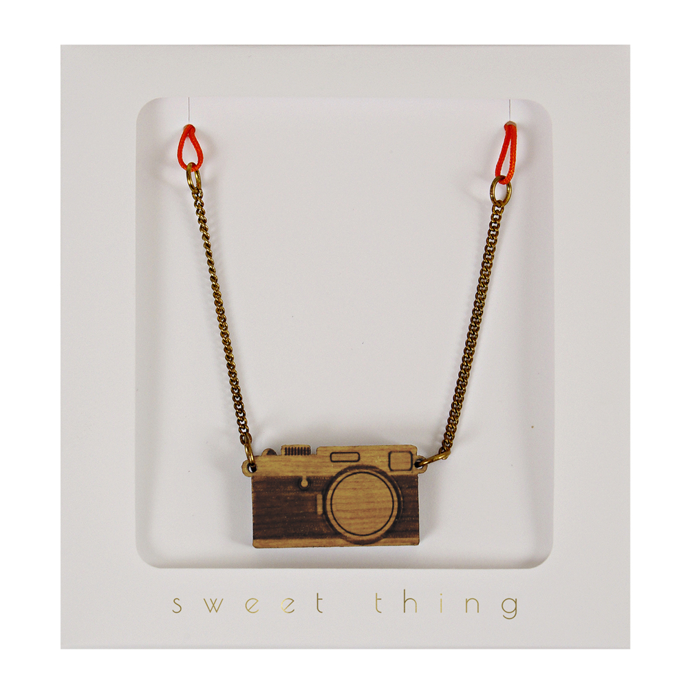 50-0001a Holzkette, Kamera-Anhänger, braun, goldene Kette, rote Bänder, Verpackung mit "sweet thing" Aufdruck.