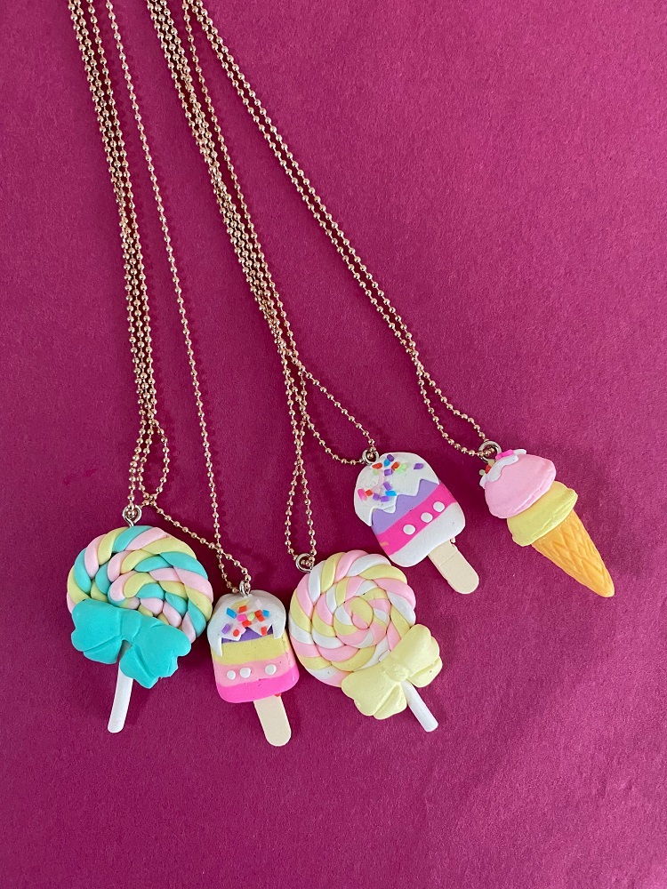 IMG_0768 Halsketten mit Anhängern in Lollipop- und Eiscremeformen, Farben: buntes Rosa, Blau, Gelb, Weiß, mit Schleifen und Streuseldekor, Ketten goldfarben.
