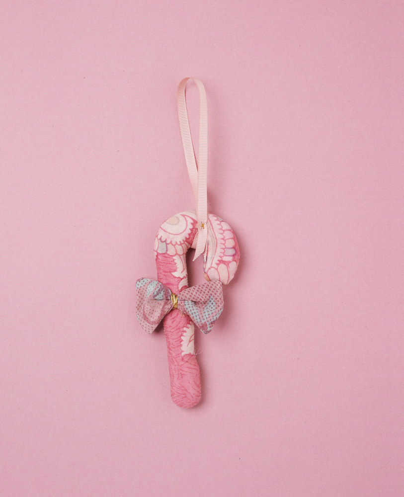 Cane-SILK-Ornament-Pearl-Pink Stoff-Zuckerstange, rosa Muster, Schleife am Stiel, Aufhängeschlaufe, pastellfarbener Hintergrund.