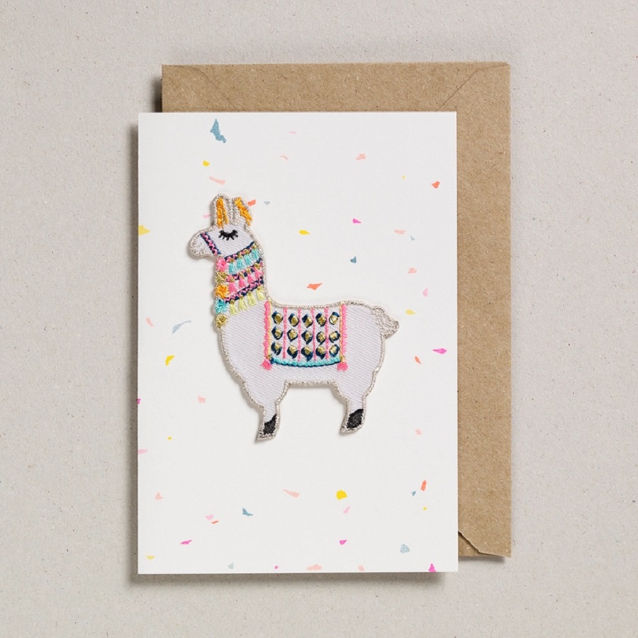ca962823b09b1a8708173a02b9242a32ee9e18b67996a035d75b2f02ce8ccf1f Postkarte, Llama-Motiv, pastellfarbene Stickerei, cremefarbenes Papier mit bunten Konfetti-Design, naturbrauner Umschlag.