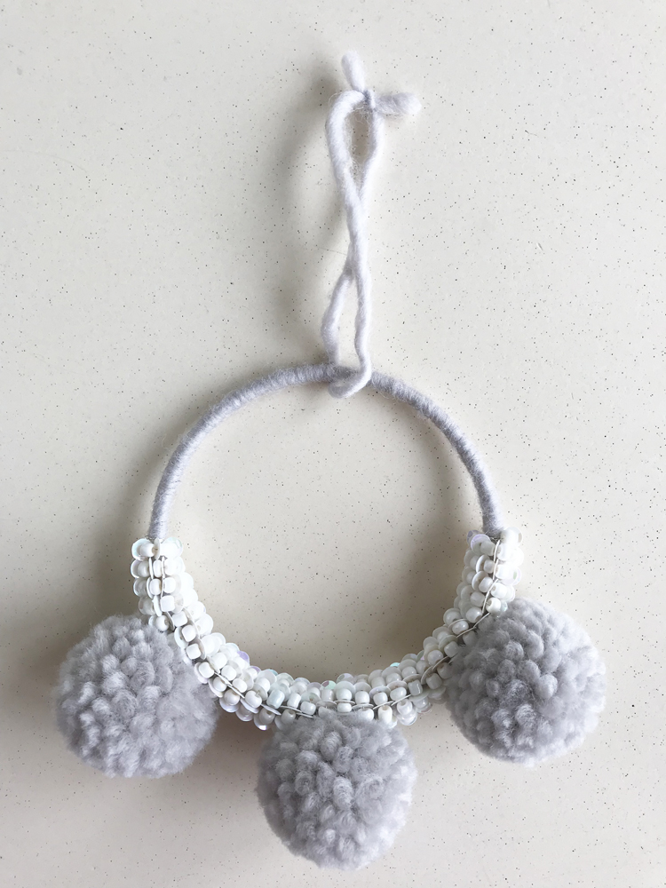 IMG_2879 Türkranz, grau, drei große Wollpompons, weiße Perlenverzierung, Aufhängeschlaufe aus Wolle.