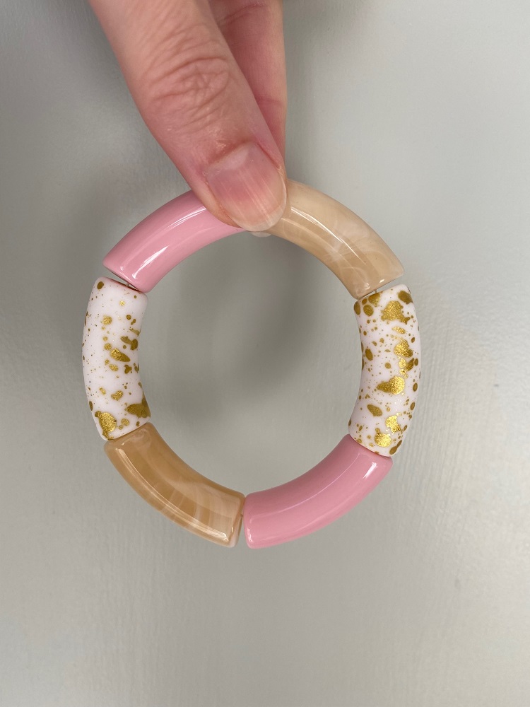 IMG_8873 Runder Armreif, Segmente in Rosa, Beige, Weiß mit goldenen Sprenkeln, glänzende Oberfläche, gehalten von Hand.