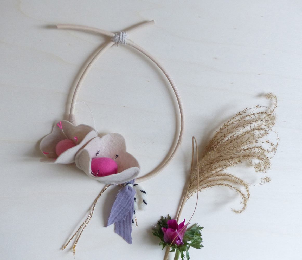 Scala-avril-mobile-fleur-2 Kranz aus Holz, dekoriert mit Filzblumen in Beige und Pink, violettes Stoffband, Trockenblume.