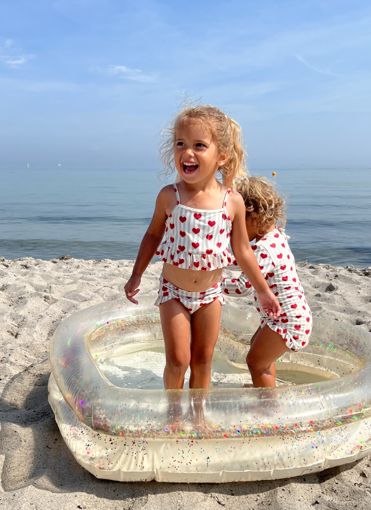 KS5195-HEART-POOL-TRANSPARENT-CREAM-Extra-2 Aufblasbares Kinderplanschbecken, transparent, Glitzer; Kinderbikini, weiß mit roten Herzen; Meereshintergrund.