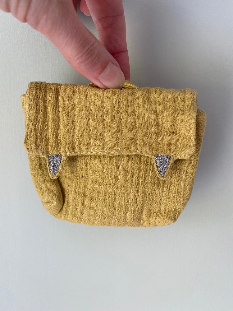 IMG_8059 Gelbe Stofftasche, kleine Größe, strukturierter Stoff, Klappe mit zwei hellgrauen Verzierungen, handgehalten.