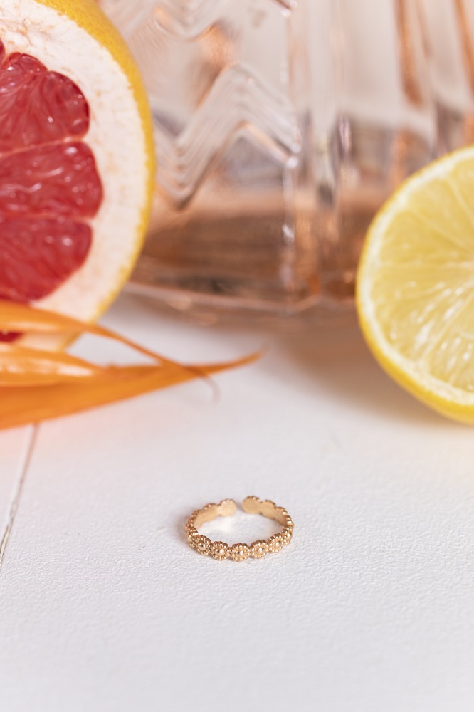 women-ring-carlett-gold-1 Ring, goldfarben, strukturiertes Design, liegend auf weißem Untergrund.