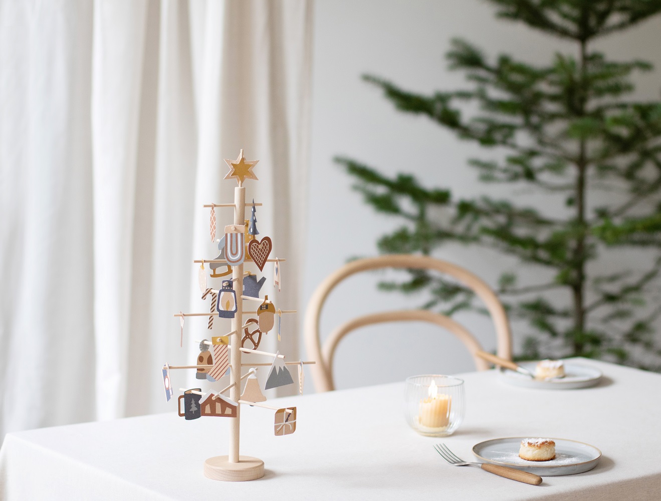 advent-tree-16 Holzbaum, Dekoration, naturfarben, Holzornamente, geometrische Formen, Sterne, Herzen, weiße Tischdecke, Kerzenlicht, Teller, Besteck.