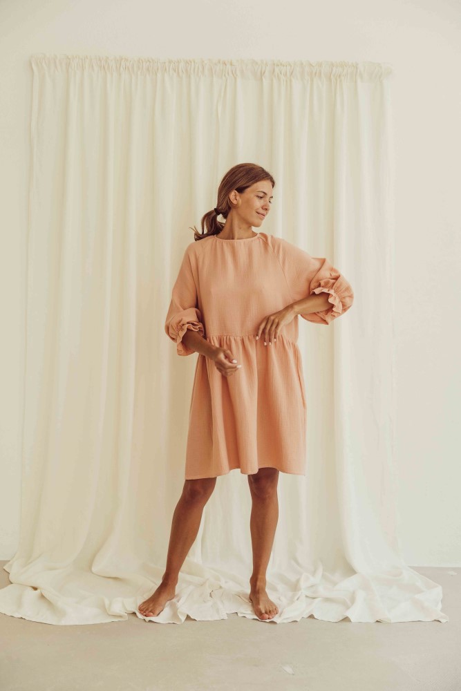 liss23_075_W_lilou-dress_peach_3 Beigefarbenes Kleid, lockerer Schnitt, Dreiviertelärmel mit Rüschen, knielang, Frau als Trägerin.