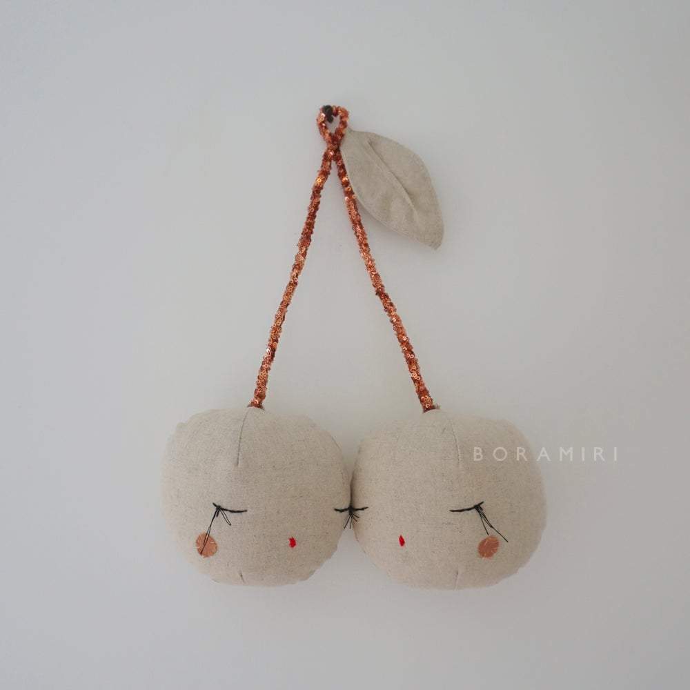 cerises_1024x1024-2x Stoffmobile, zwei cremefarbene Kirschen mit geschlossenen Augen, rosegoldene Glitzerstiele, beiges Blatt, minimalistisches Design.