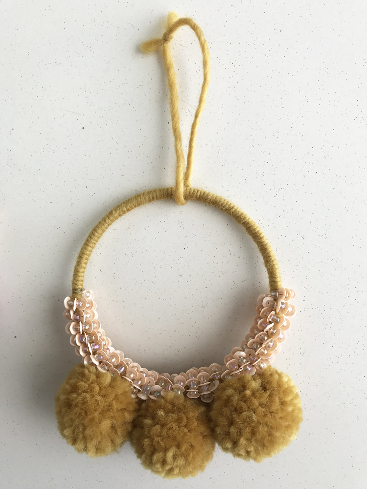 IMG_2913 Dekoration; Ring aus gelbem Garn; drei gelbe Pompons; rosa Paillettenverzierung; Aufhänger aus gelbem Garn.
