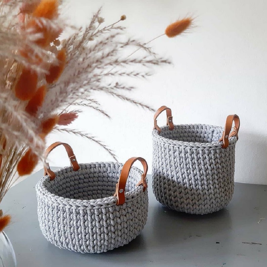 il_794xN-2841537421_ht8s Zwei gehäkelte Körbe, grau, mit braunen Ledergriffen, runde Form, unterschiedliche Größen.