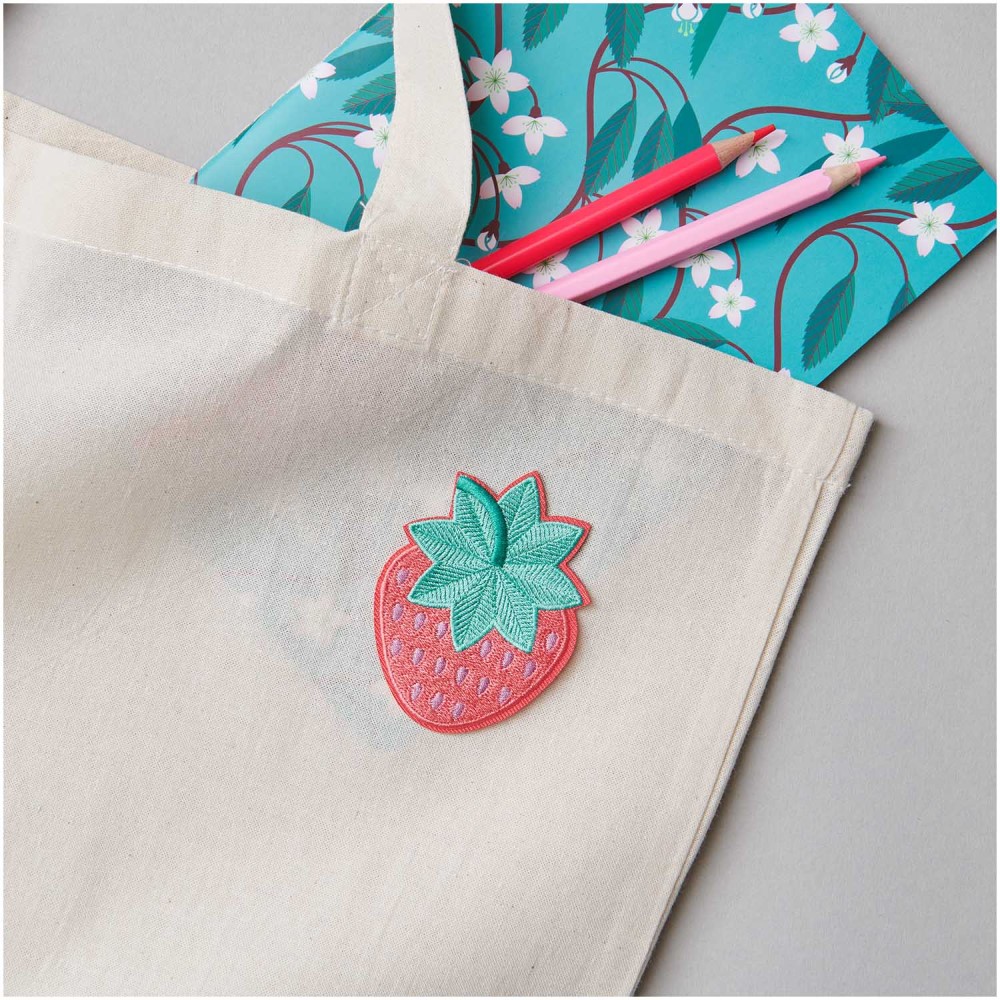 280084_aw_1 Beige Stofftasche, Erdbeerapplikation vorne, blumiges Notizbuch und zwei Buntstifte in der Tasche.