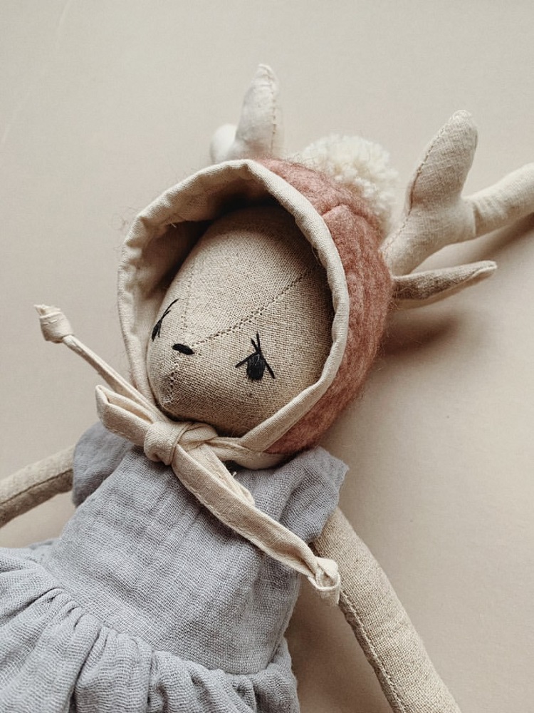038B9CBA-417B-4AFE-BE89-40C429229F7E-002 Stoffpuppe, Reh, beiger Stoff, rosa Mütze mit Geweih, graues Kleid, Schleife am Hals.