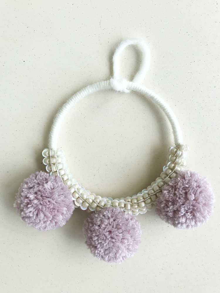 IMG_2851 weißer Wickelring, drei lila Pompons, Perlenverzierung