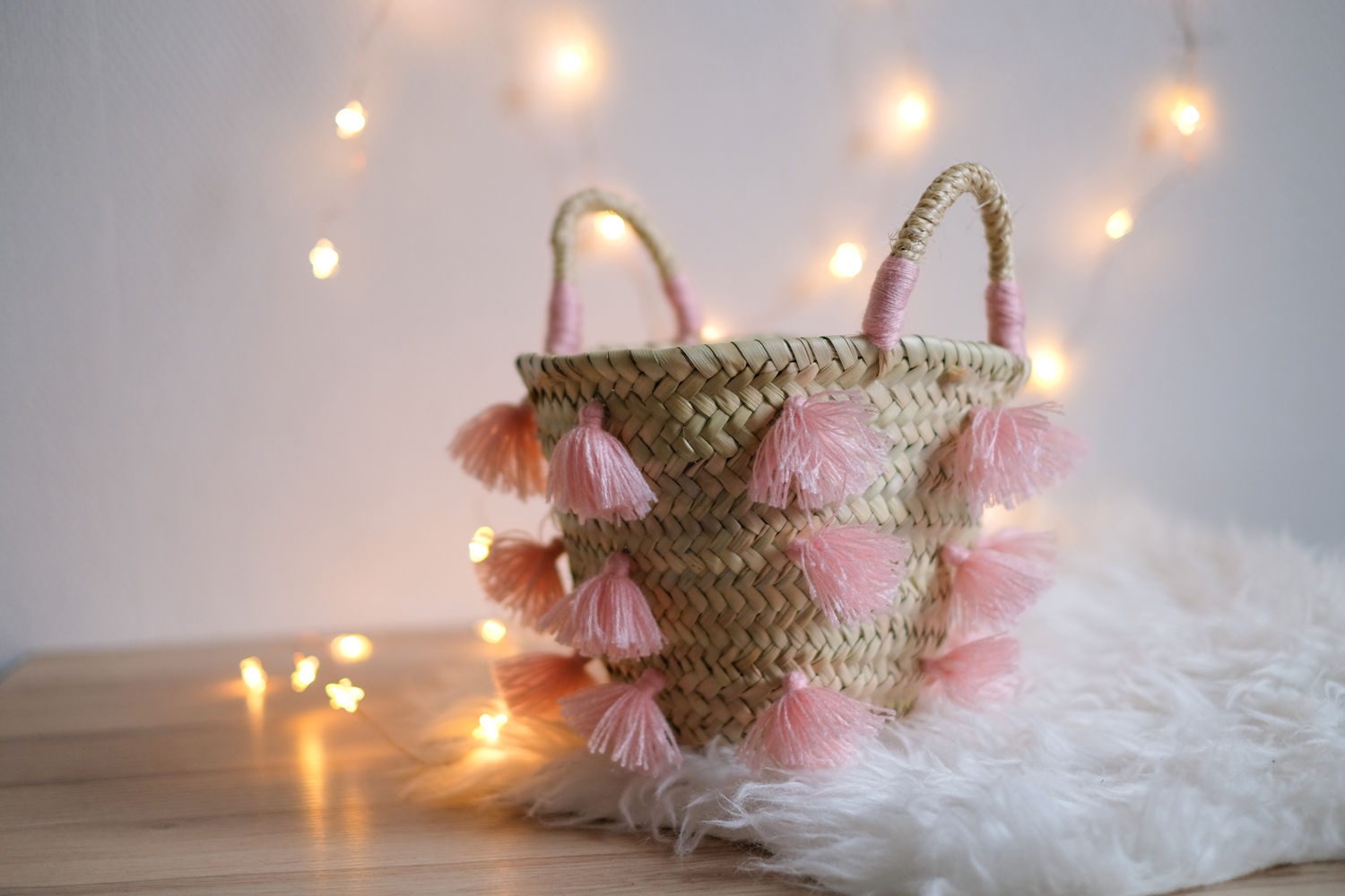 MOTI_BLOSSOM_2 Korb, geflochten, beige, rosa Quasten, Griffe mit rosa Garn umwickelt.