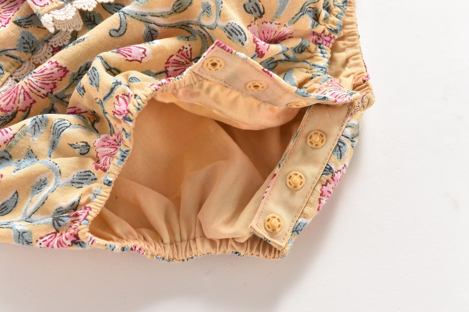 baby-girl-rompers-kumal-lemon-flowers-4 Blumige Babyhose, gelb, rosa Blumenmuster, Druckknöpfe, elastischer Bund, Spitzeinsatz.