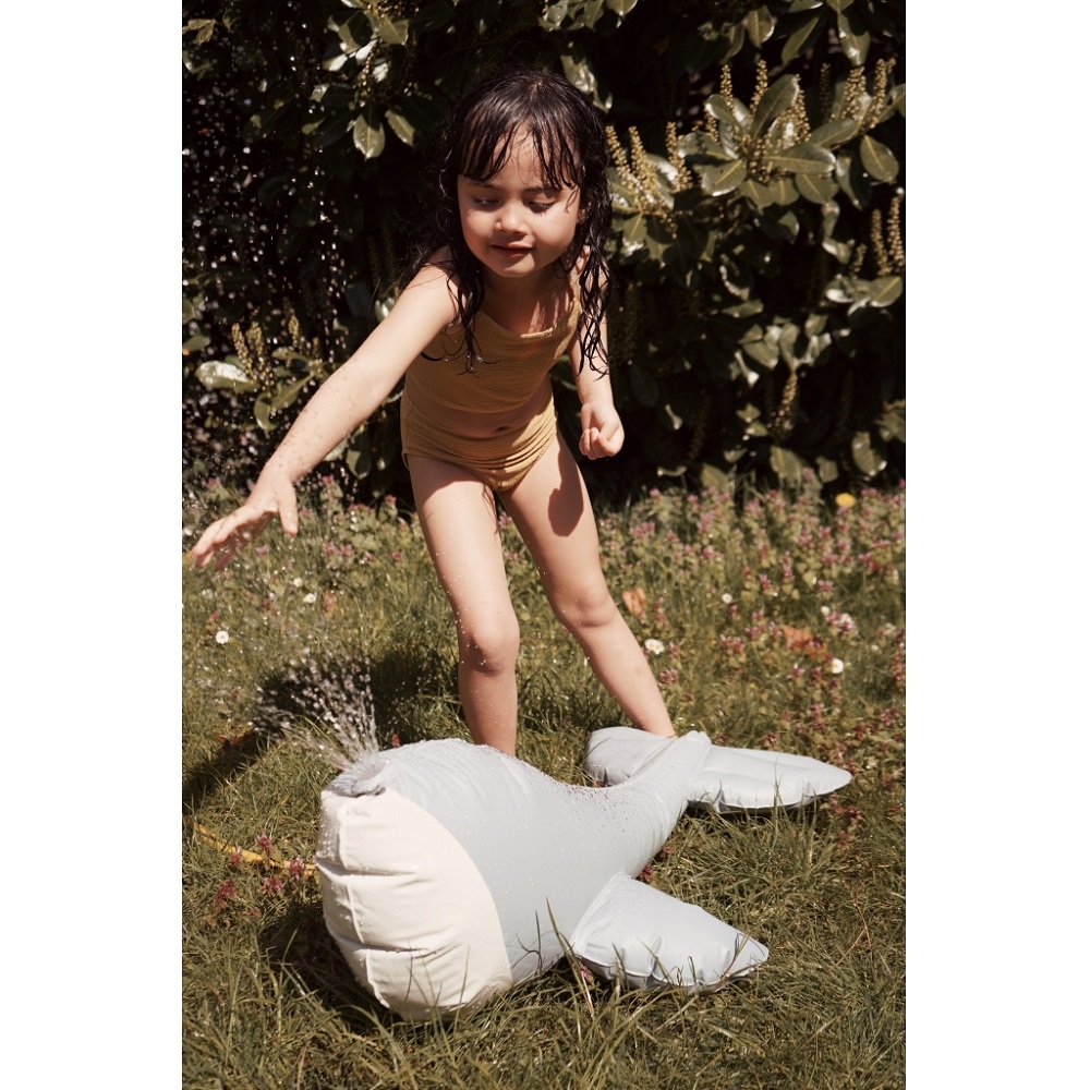 1024x1024-18579c67ee0560898e5deba4037faaff Aufblasbarer grauer Wal, Wasserfontänen am Kopf, im Garten verwendet. Spielendes Kind in hellbraunem Badeanzug.