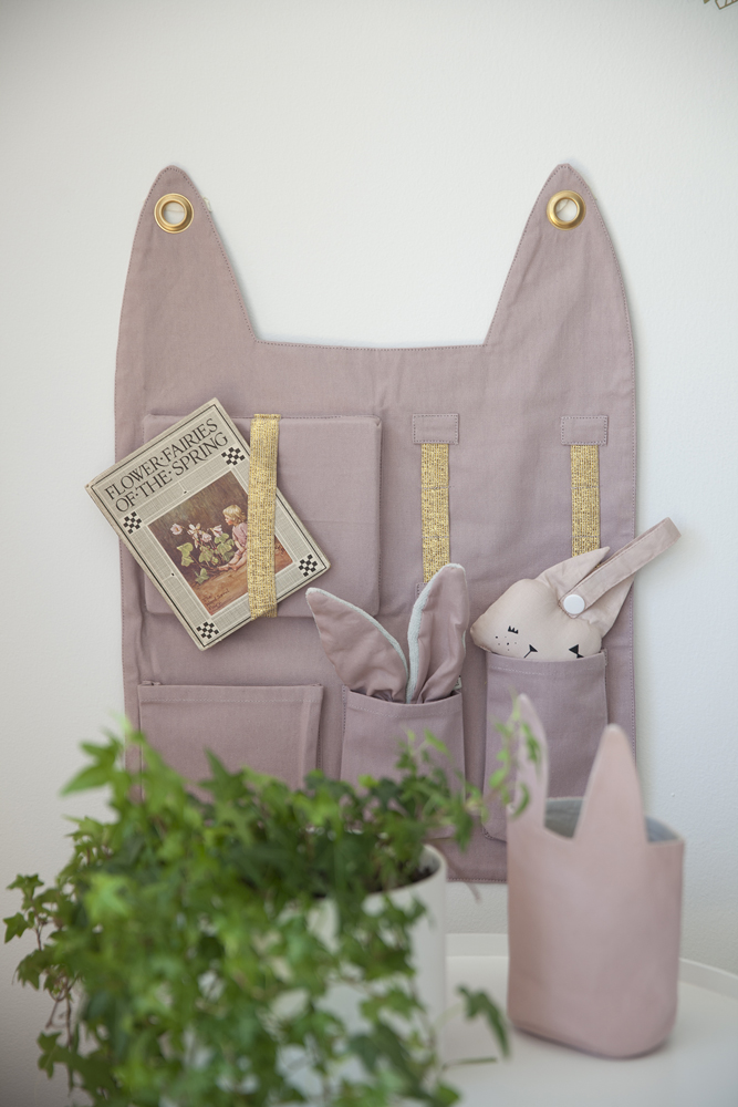 IMG_1525 Organizer, Stoff, lila, Wandbehang, mehrere Taschen, goldfarbene Aufhängungen, Hasenohren-Dekor, kleines Plüschtier in Form eines Kaninchens, Buch in Außentasche.