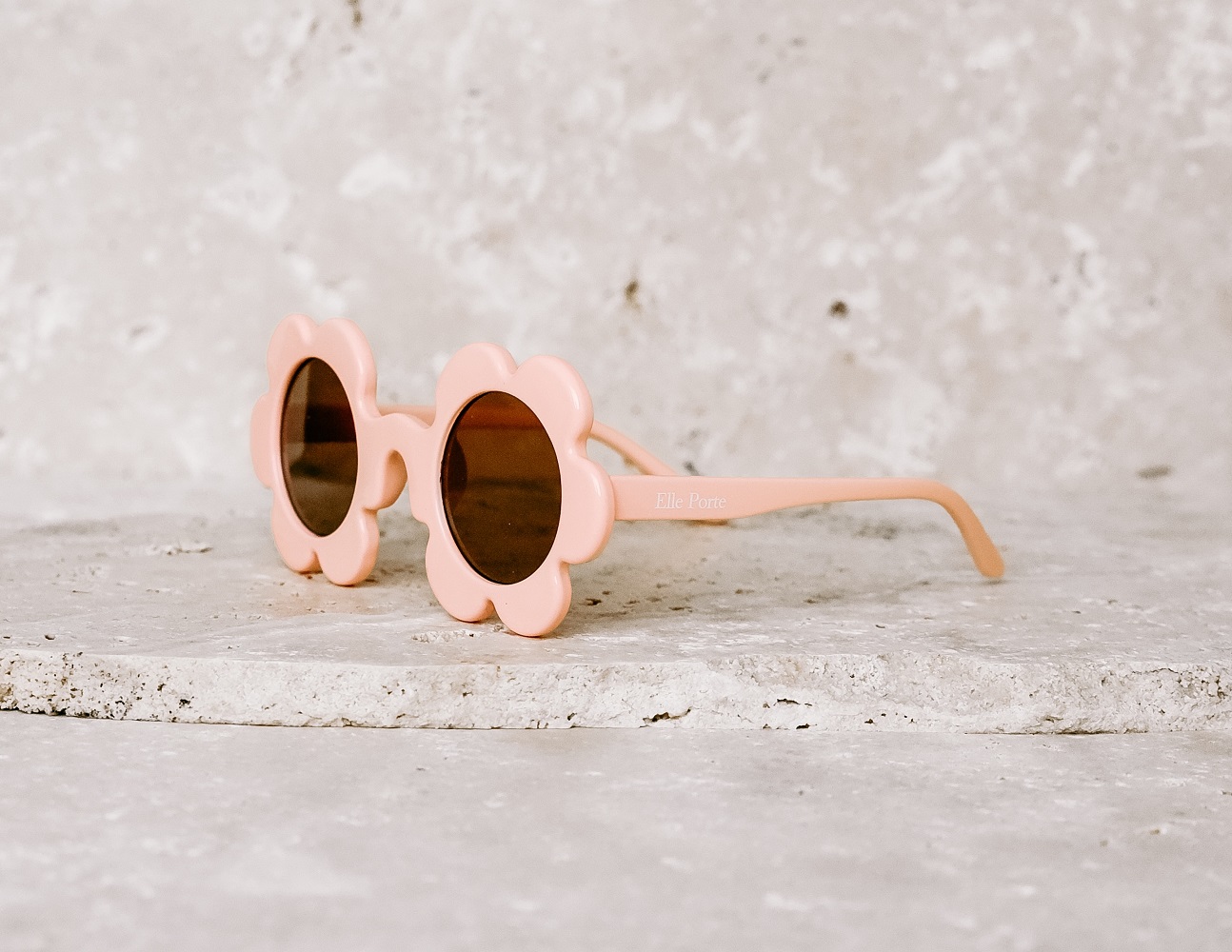 39ORANGEFIZZ_1 Sonnenbrille, rosa, Blumendesign, runde Gläser, Kunststoffgestell, beige Hintergrund.