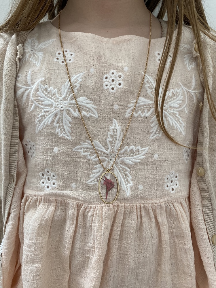 IMG_2617 Halskette mit ovalem Anhänger, florales Design; Kleid aus cremefarbener Spitze, Stickereien in weiß; beige Strickjacke.