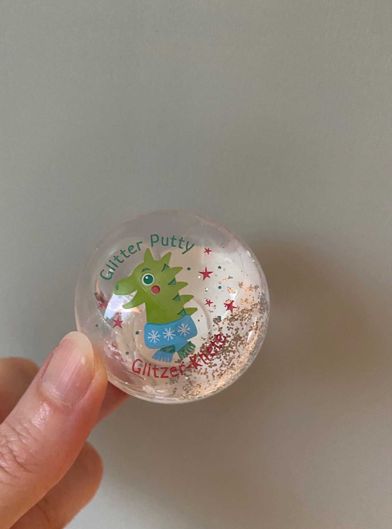 Klarer Behälter, Glitzerknete, grüner Dinosaurieraufdruck, blauer Rock mit Schneeflockenmuster, bunte Sterne.
