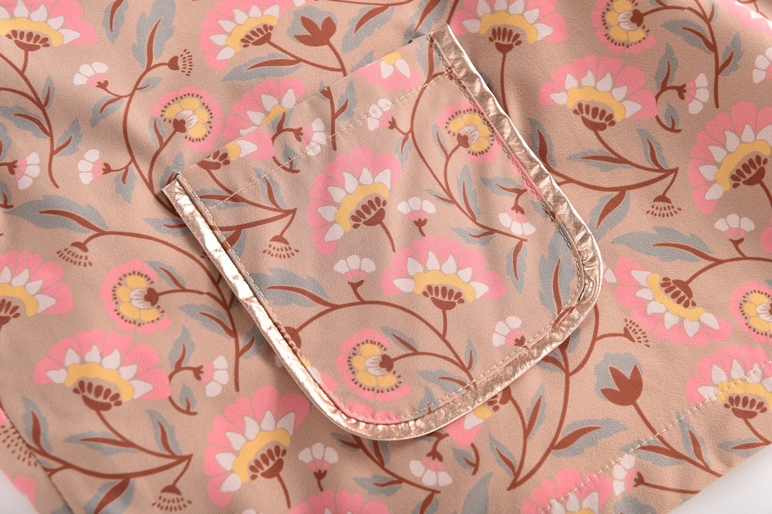 Girls-Raincoat-Mara-KhakiFolkFlowers-9 Beigefarbene Tasche, Blumenmuster in Rosa, Gelb, Weiß und Braun, glänzende Paspelierung, modern und dekorativ.