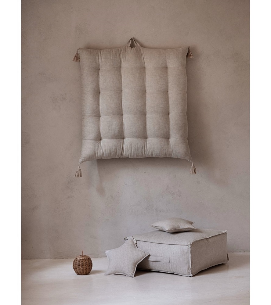 lniany-materac-z-chwostami-naturalny-bez-1 Großes beigefarbenes, quadratisches Sitzkissen auf Boden und passender Wandteppich, beide mit Quasten; kleine Kissen in Stern- und Quadratform; runder geflochtener Korb; minimalistische Einrichtung.