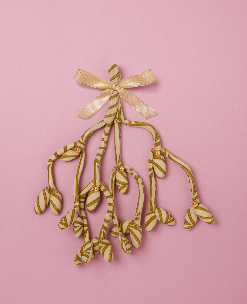 Mathilda-SILK-Mistletoe-Olive-Branch Misteldekoration aus Stoff, grün-weiß gestreift, goldene Schleife, goldene Perlendetails, rosa Hintergrund.