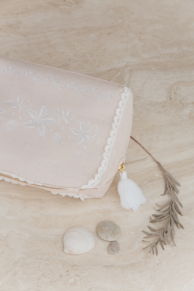 home-large-pocket-teiki-blush-2 Kosmetiktasche, beige, florale Stickerei, Spitzenbordüre, goldener Reißverschluss, weißer Quastenanhänger.