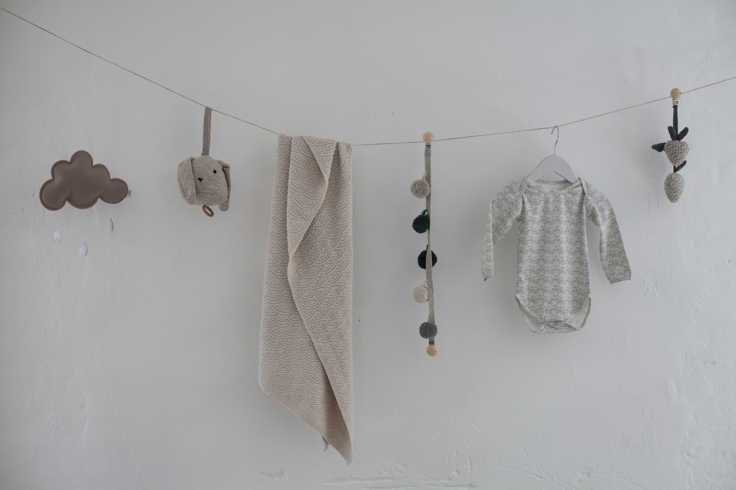 149 Wolkenförmige Wanddekoration, beige Babydecke mit Strukturmuster, grauer Strickbody, Stoffball-Girlande, gehäkelte Tierfigur.