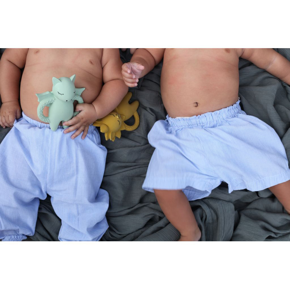 KS1222-Extra-3 Babykleidung, blaue gestreifte Shorts, zwei Babys, Spielzeugtier grün und ein Spielzeugtier senfgelb in Katzenform, grauer Hintergrund.