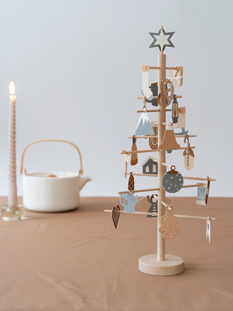 advent-tree-natural Holz-Weihnachtsbaum, naturfarben, rund, mit Sternspitze, dekoriert mit Holzanhängern in Beige, Blau, Grau, Rot, verschiedene Formen wie Herz, Kreis, Haus, Tanne, Berg, auf braunem Tisch platziert.