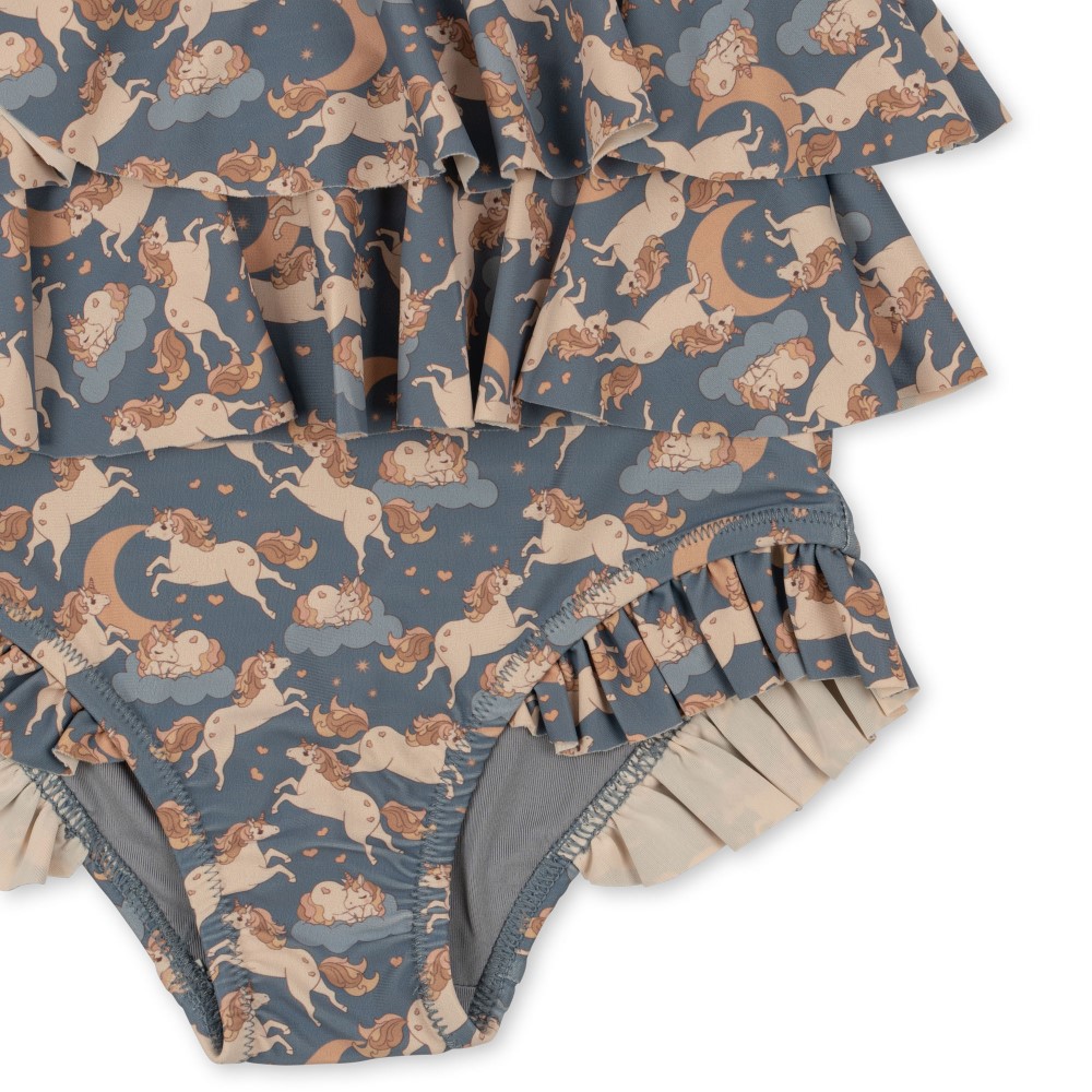 KS4697-MANUCA-FRILL-SWIMSUIT-UNICORN-BLUE-Extra-5 Badeanzug, dunkles Blau, Allover-Einhorn-Muster, Rüschen-Dekor, pastellfarbene Einhörner auf Wolken mit Monden und Herzen.